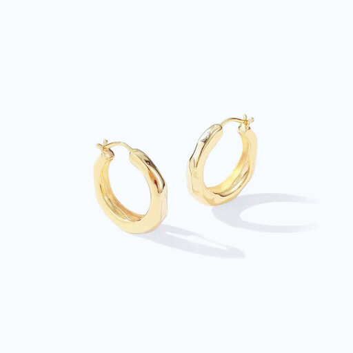 A pair of chunky gold hoop earrings with an irregular, wavy design