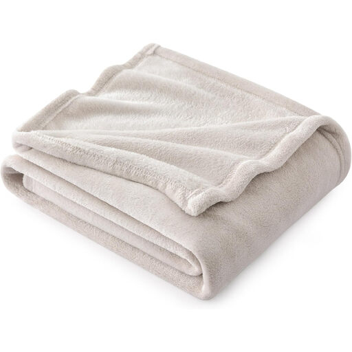 A beige, fluffy fleece blanket shown in a home setting.