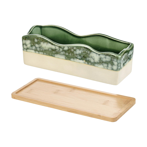 A rectangular, beige-green glazed ceramic planter with a wavy rim, filled with succulents, sits on a bamboo tray.